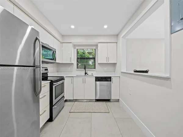 a kitchen with granite countertop a refrigerator and a stove top oven