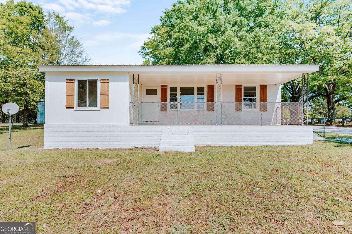 a front view of house with yard and trees in the background