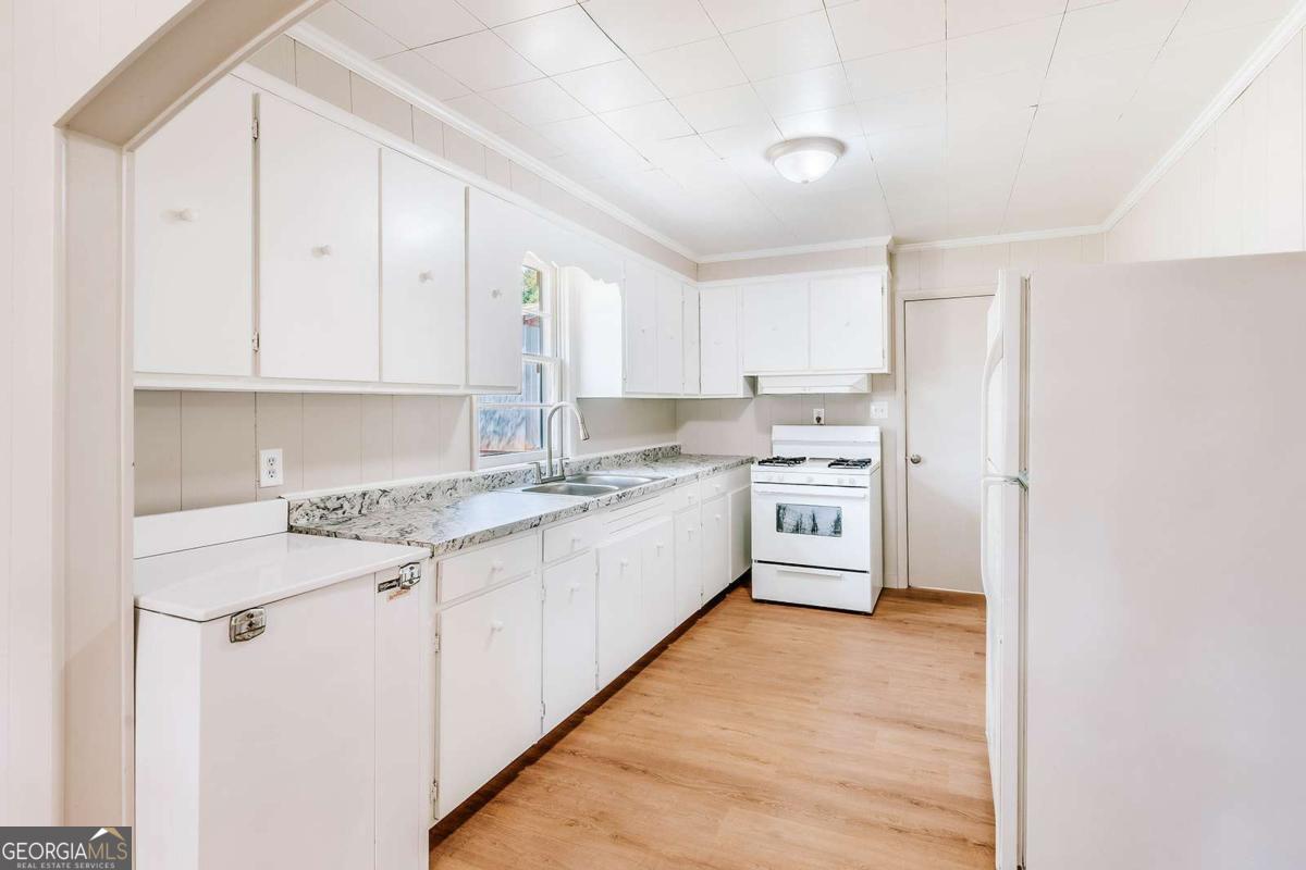 52 Clark Circle Lexington, GA 30648 - Photo 11 of 47 a large white kitchen with stainless steel appliances granite countertop a stove a sink and white cabinets