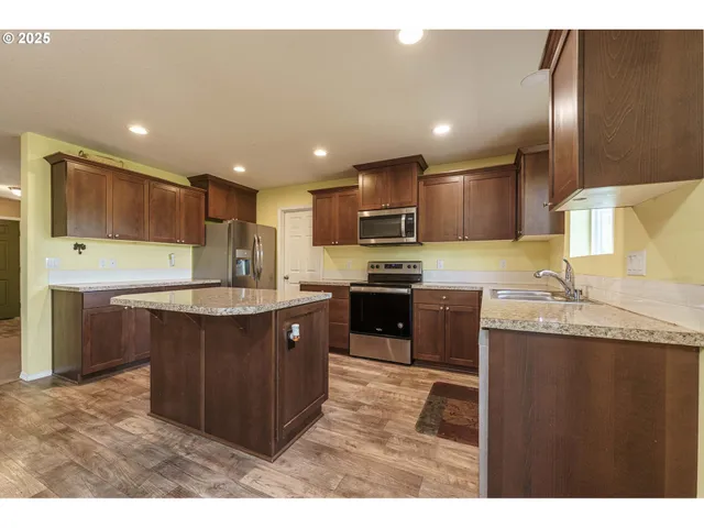 a kitchen with kitchen island granite countertop wooden cabinets a sink and a stove
