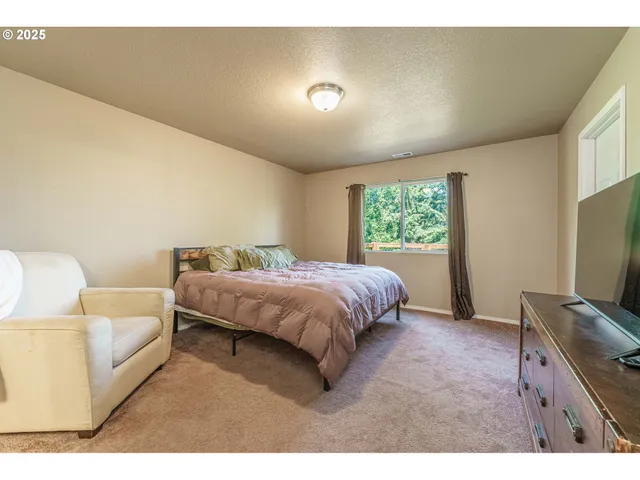 a spacious bedroom with a bed and a flat screen tv