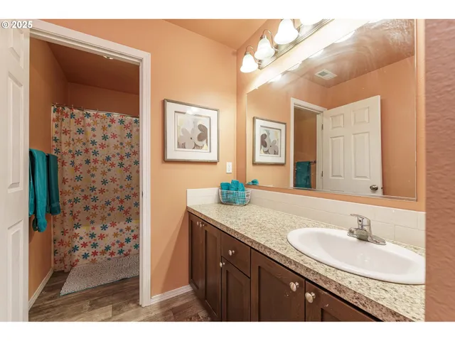a bathroom with a granite countertop sink a mirror a vanity and shower