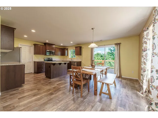 a open dining room with kitchen island furniture a large window and wooden floor