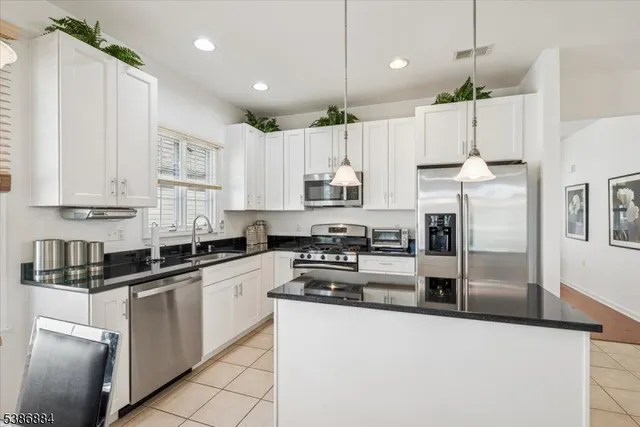 a kitchen with kitchen island granite countertop a white cabinets and refrigerator