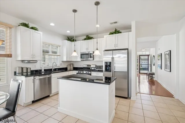 a kitchen with stainless steel appliances granite countertop a refrigerator a stove a sink and white cabinets