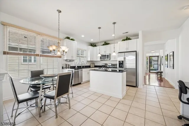 a kitchen with stainless steel appliances kitchen island granite countertop a table chairs and a view of living room