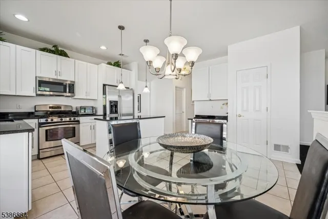 a kitchen with stainless steel appliances kitchen island granite countertop a table chairs and a refrigerator