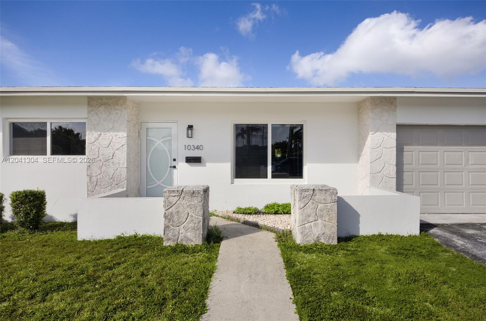 10340 Southwest 157th Street Miami, FL 33157 - Photo 2 of 24 Front Entry – Inviting covered entrance featuring decorative stone accents and a modern frosted-glass front door. Thoughtfully designed details create a polished arrival experience.