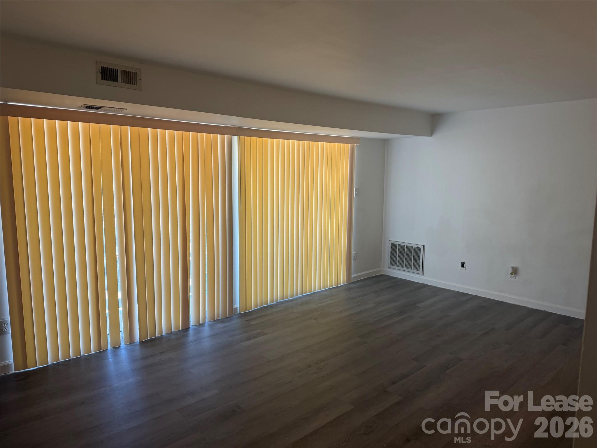 9333 Old Concord Road, Unit J Charlotte, NC 28213 - Photo 4 of 18 an empty room with wooden floor and windows with curtains