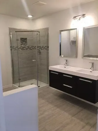 a bathroom with a double vanity sink mirror and shower