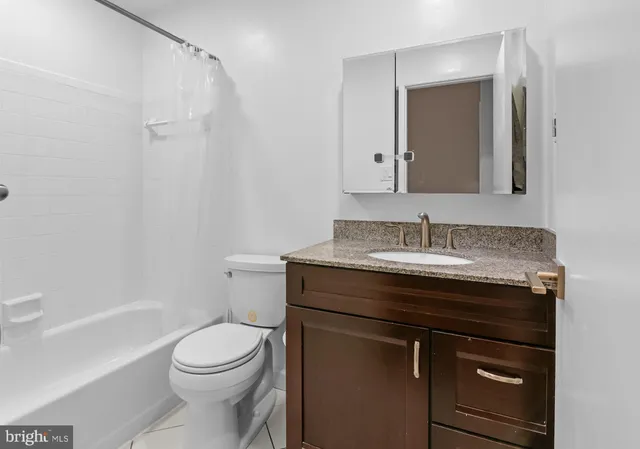 a bathroom with a granite countertop sink toilet a mirror and shower
