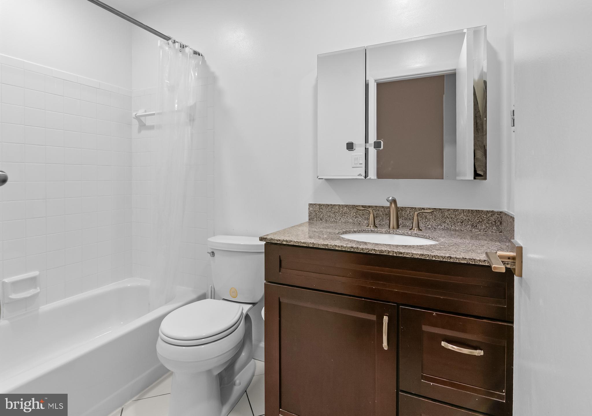6939 Copper Bend Lane Baltimore, MD 21209 - Photo 12 of 18 a bathroom with a granite countertop sink toilet a mirror and shower