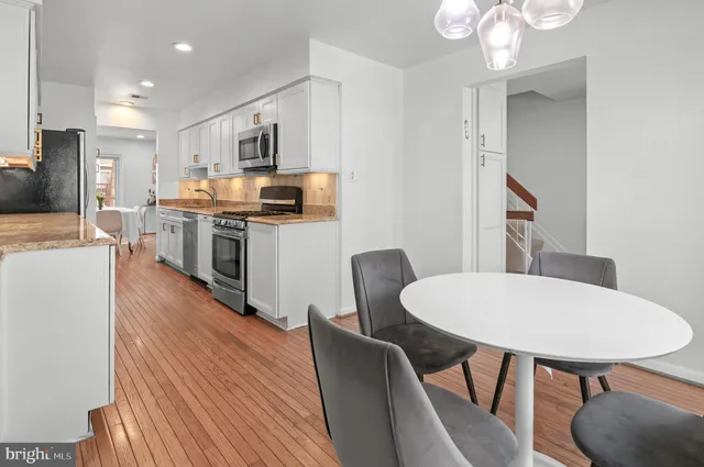 a kitchen with stainless steel appliances granite countertop a dining table chairs stove refrigerator and cabinets