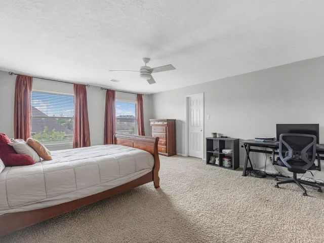 a bedroom with a bed a large window with table and chair
