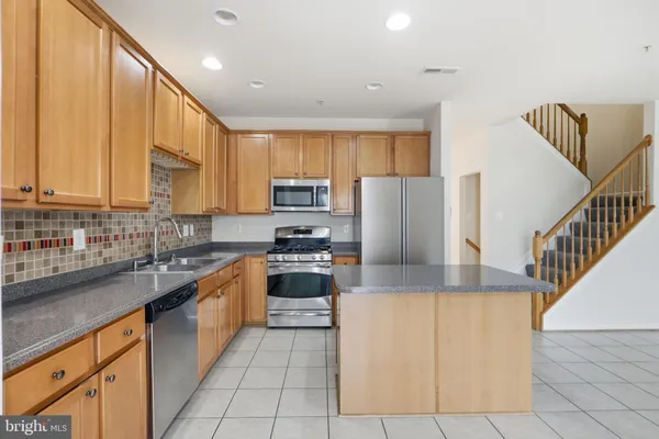 a kitchen with stainless steel appliances granite countertop a refrigerator a stove top oven a sink and dishwasher