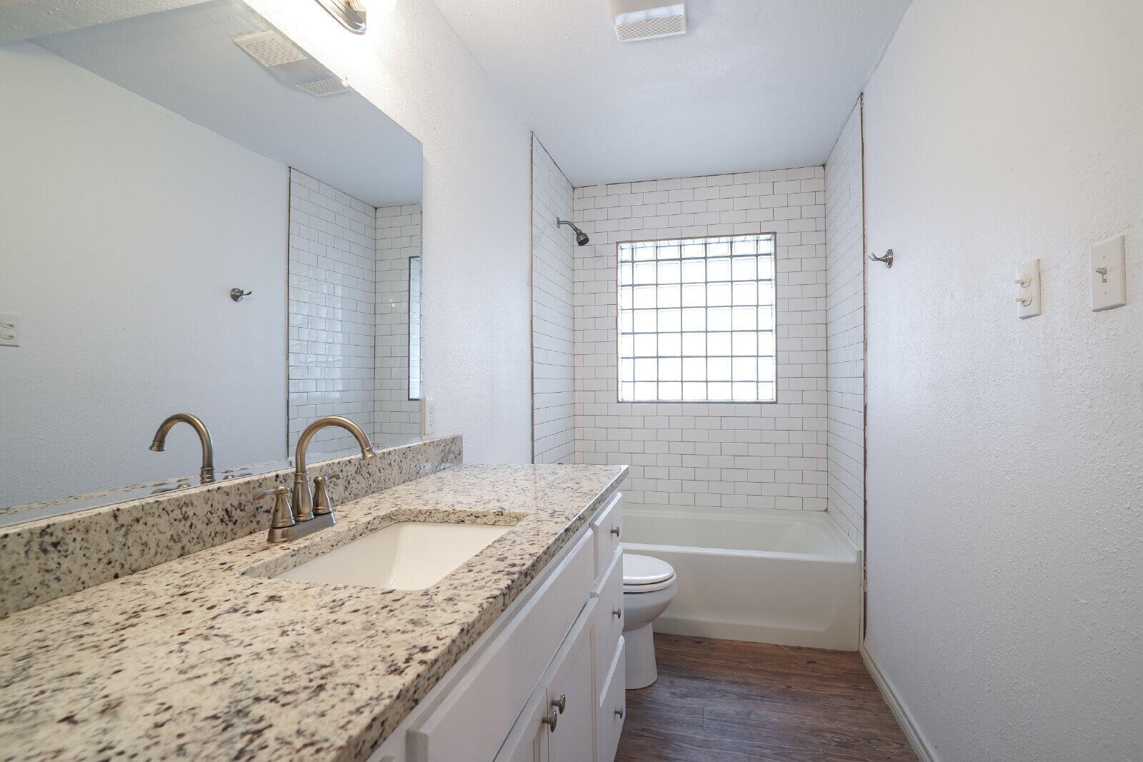 2826 54th Street Lubbock, TX 79413 - Photo 27 of 32 a bathroom with a granite countertop sink a toilet and shower