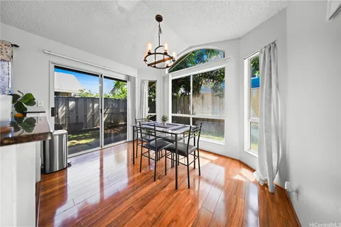 a dining room with wooden floor a chandelier a glass table and chairs