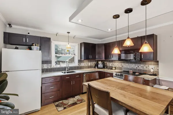 a kitchen with a sink a stove a refrigerator and black cabinets