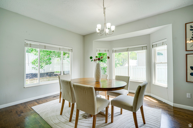 1433 Forge Way Draper, UT 84020 - Photo 7 of 29 Dining area featuring a bay window, wood-finish flooring, light grey walls, and a multi-arm chandelier