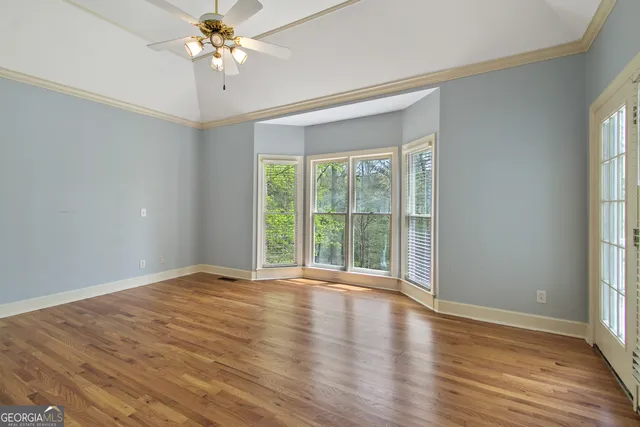 a view of an empty room with wooden floor and a window