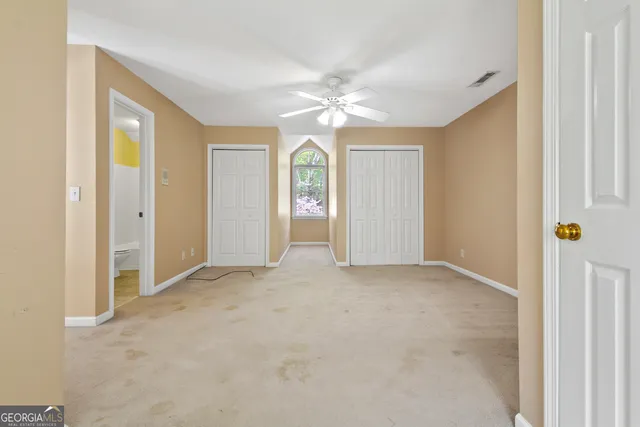 an empty room with fan and windows
