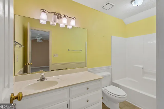 a bathroom with a granite countertop sink a toilet and shower