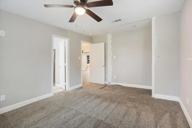 a view of an empty room and chandelier fan