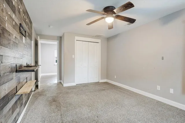 an empty room with chandelier fan and windows