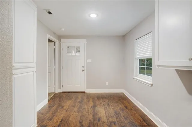 an empty room with wooden floor and windows