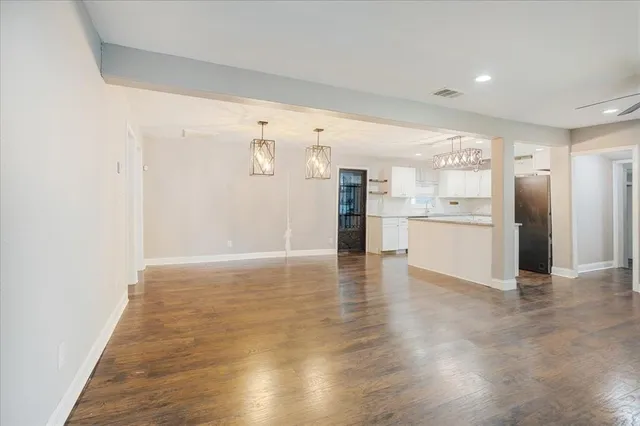 a view of a electric appliances in kitchen and empty room with wooden floor