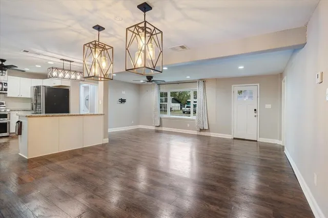 an empty room with wooden floor and kitchen view