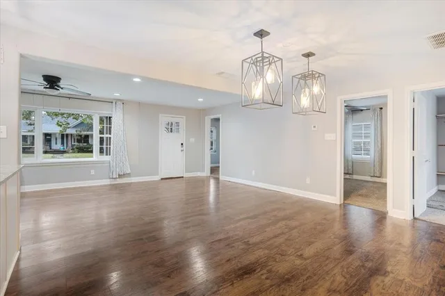 a view of an empty room with wooden floor and chandelier
