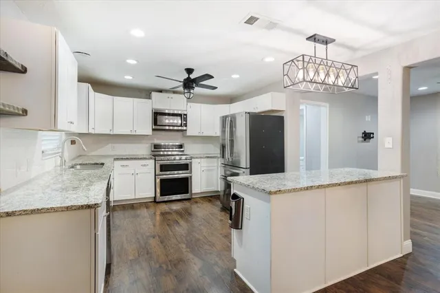 a kitchen with kitchen island granite countertop stainless steel appliances a stove refrigerator sink and microwave
