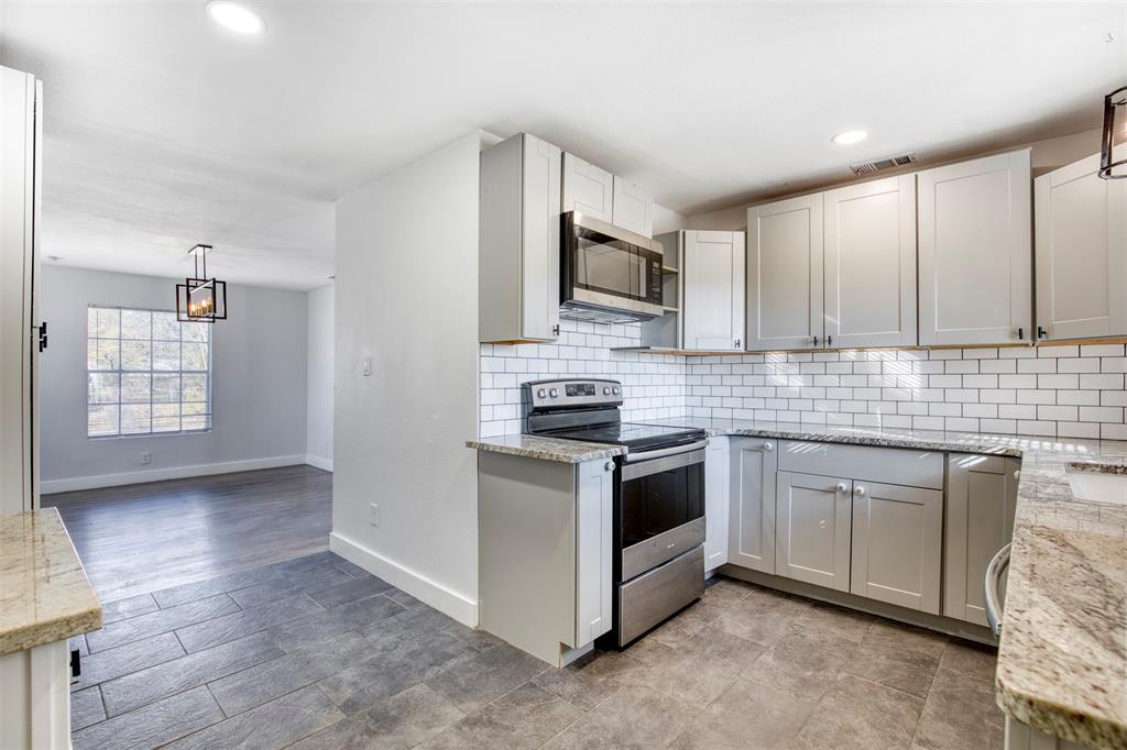 903 West 8th Street Bonham, TX 75418 - Photo 11 of 21 a kitchen with stainless steel appliances granite countertop a stove a sink and a microwave