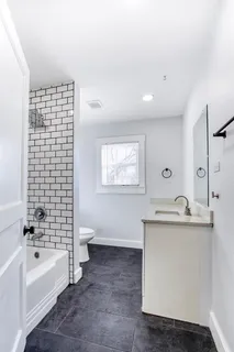 a bathroom with a granite countertop sink a toilet and bathtub