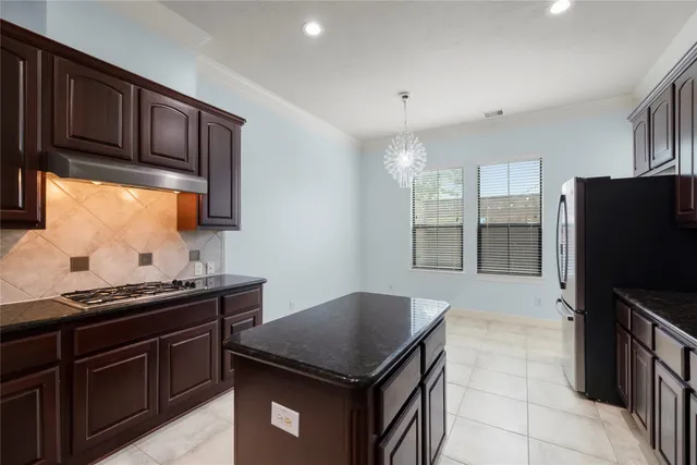 a kitchen with granite countertop a stove refrigerator and cabinets