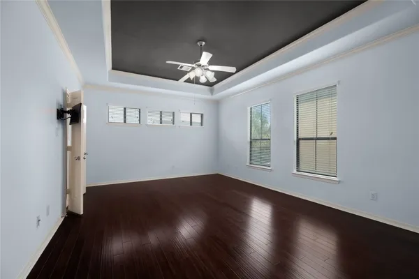 an empty room with wooden floor chandelier fan and windows