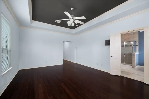 a view of an empty room with wooden floor and a ceiling fan