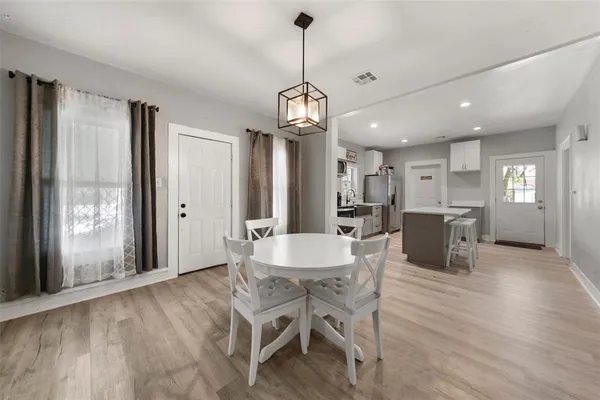 a dining room with furniture a chandelier and wooden floor
