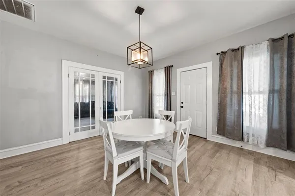 a dining room with wooden floor a chandelier a wooden table and chairs