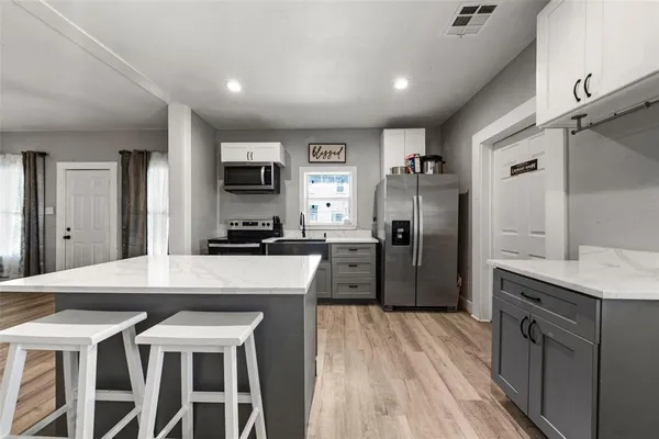 a kitchen with kitchen island a counter top space a sink stainless steel appliances and cabinets