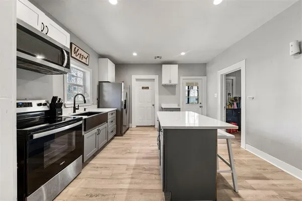 a large kitchen with stainless steel appliances kitchen island granite countertop a stove and a refrigerator