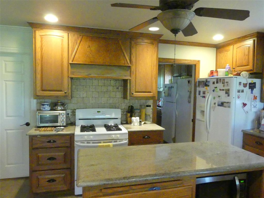3421 Schoolhouse Road Forestburg, TX 76239 - Photo 8 of 39 a kitchen with stainless steel appliances kitchen island granite countertop a refrigerator a stove and a sink