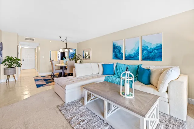 a living room with furniture potted plant and kitchen view