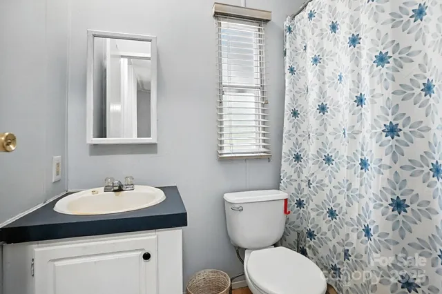 a bathroom with a granite countertop toilet a sink and a mirror