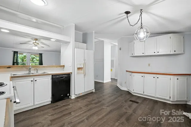 a kitchen with wooden floor white cabinets and stainless steel appliances