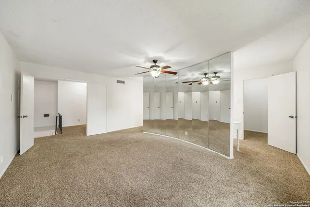 a view of a livingroom with a chandelier fan and kitchen view