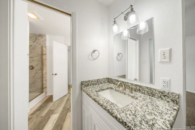 a bathroom with a granite countertop sink a mirror and a shower