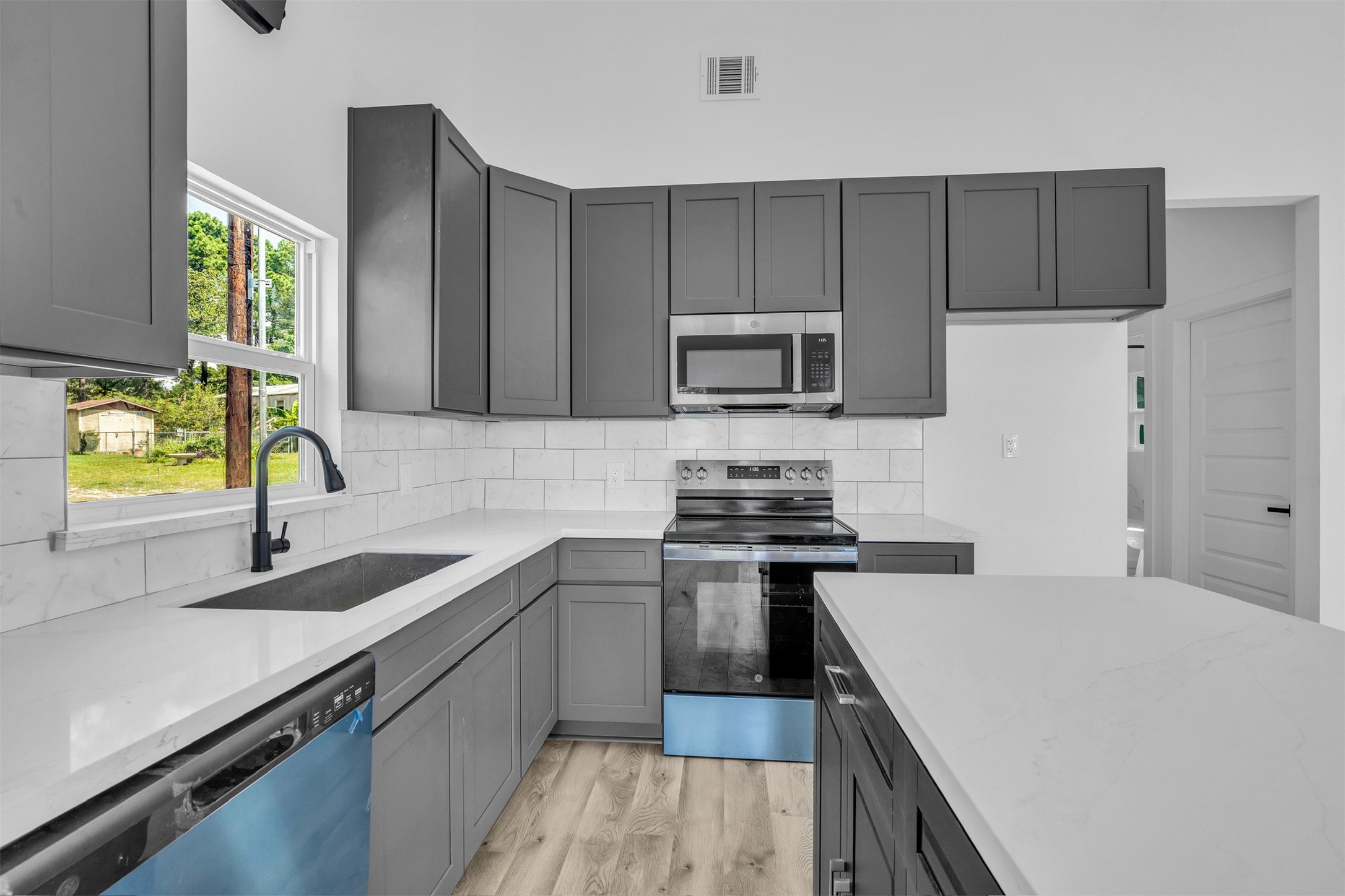 117 Rain Forest Road Onalaska, TX 77360 - Photo 13 of 30 Modern kitchen with sleek gray cabinetry, stainless steel appliances, and white countertops offering a clean, contemporary look.