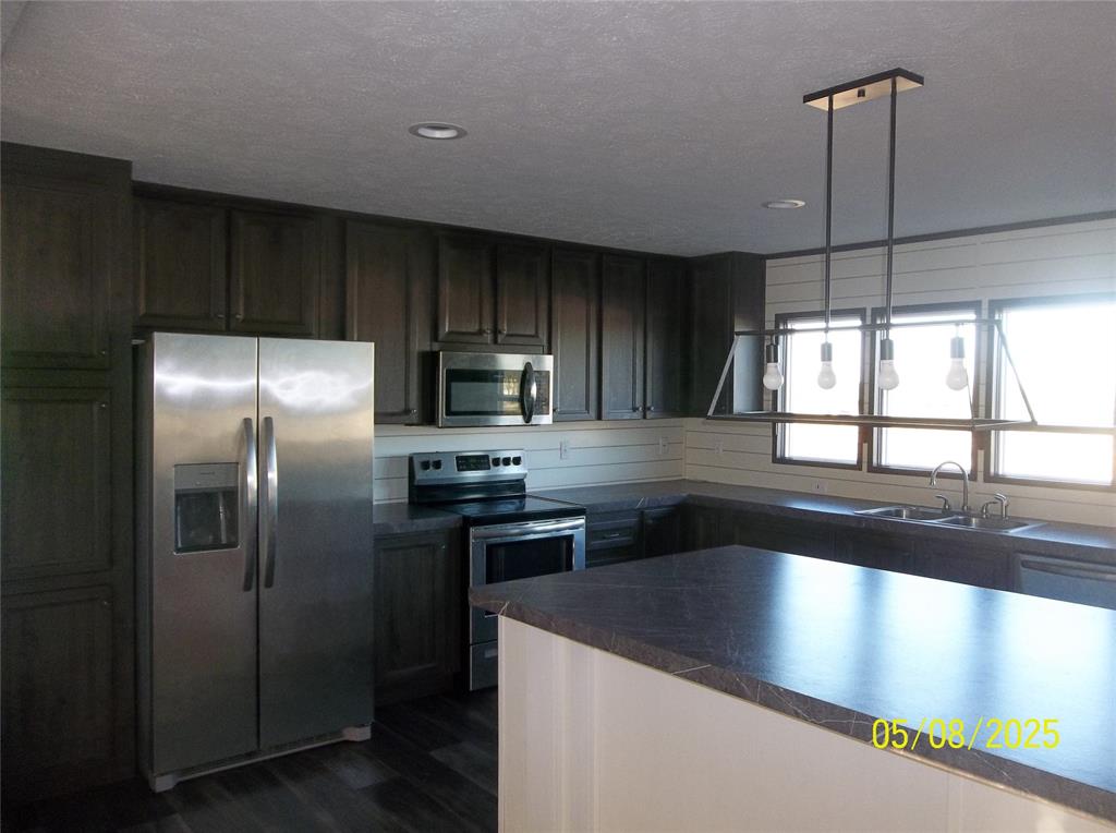 531 Blair Road Waxahachie, TX 75165 - Photo 18 of 40 Kitchen featuring stainless steel appliances, dark countertops, hanging light fixtures, dark wood-type flooring, and dark wood finish cabinetry